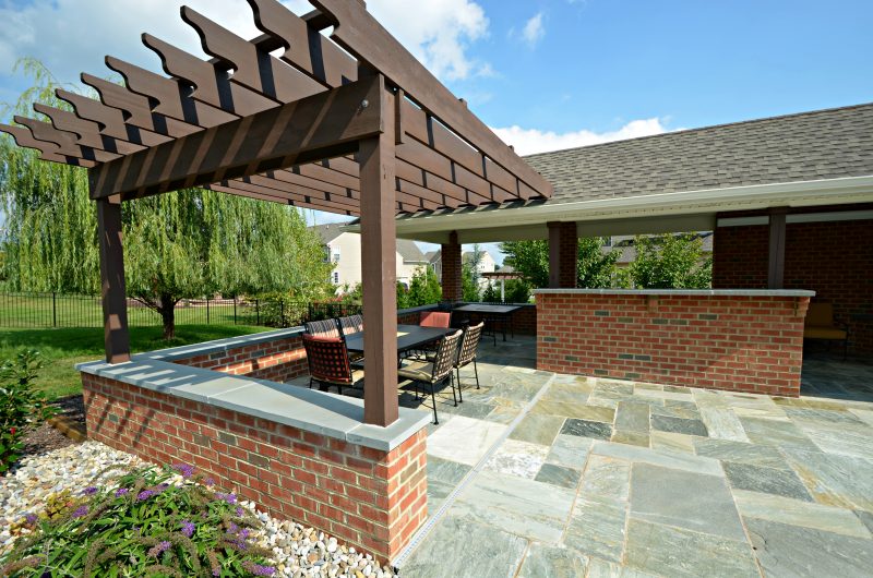 backyard stone patio with wooden pergola